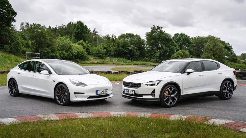 Vit Tesla Model 3 står med nosen mot en vit Polestar 2 parkerade i en kurva på en motorbana.
