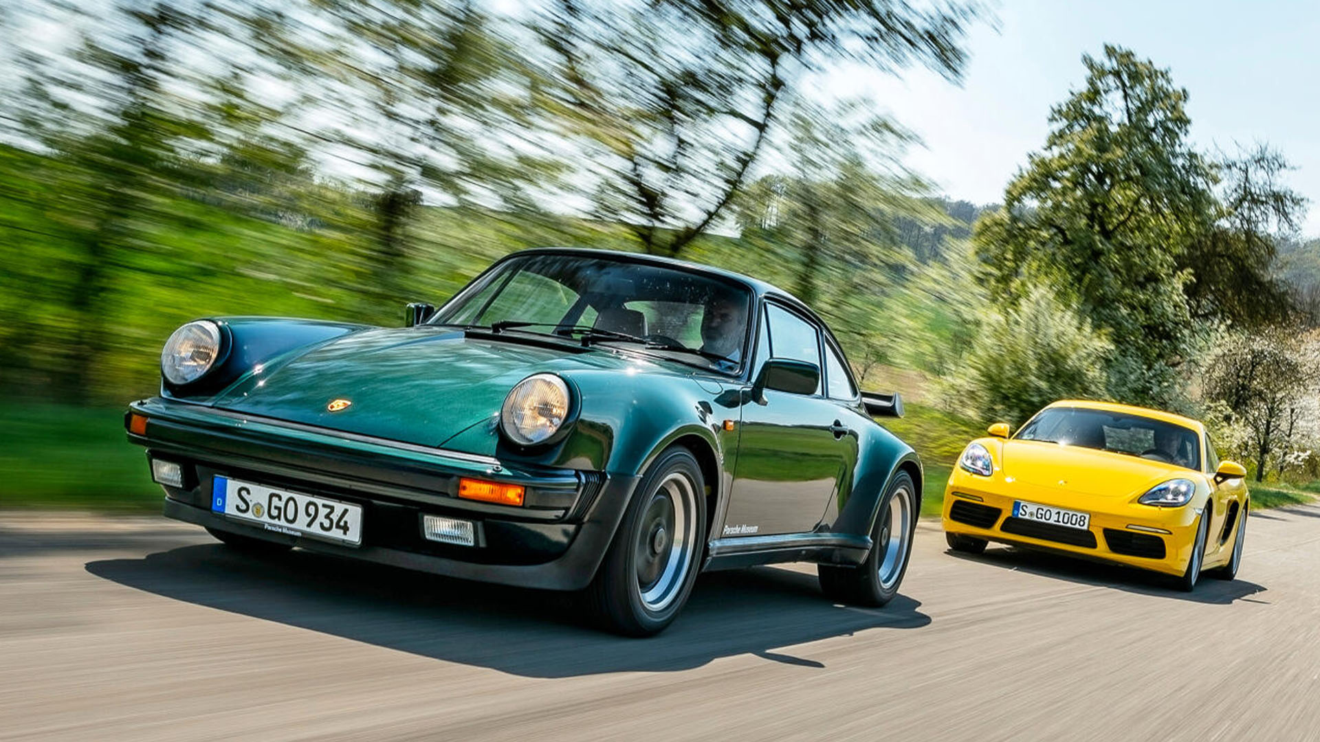 Två Porsche 911 kör längs en landsväg. (AI text)