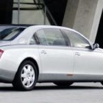 En silverfärgad Mercedes-Benz S-klass parkerad framför ett byggnad. (AI text)