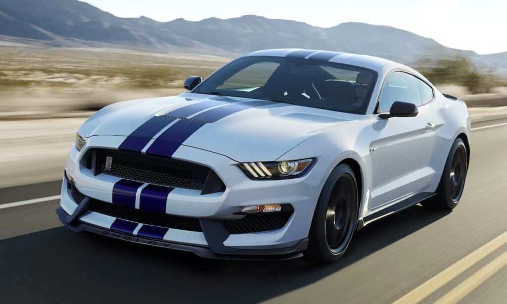 En vit Ford Mustang GT kör genom en ökenväg. (AI text)