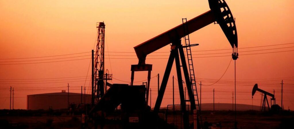 En man står framför en oljepump vid solnedgången. (AI text)