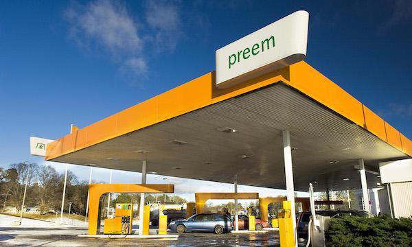 En bensinstation med en bil framför den. (AI text)