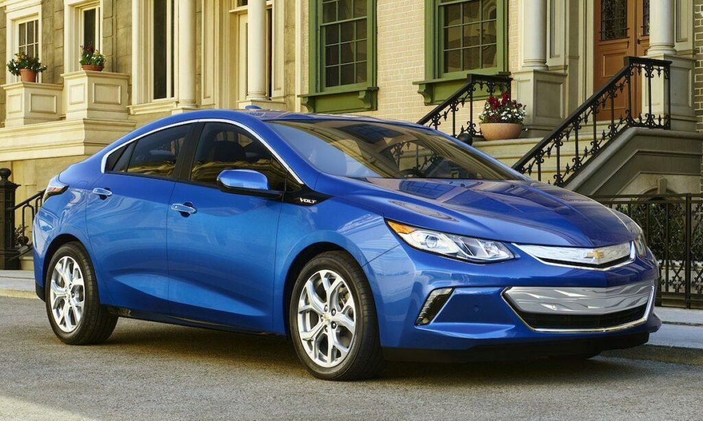 En blå Chevrolet Volt parkerad framför en byggnad. (AI text)