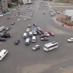 luftbild av en stadsgata med bilar och folk (AI text)