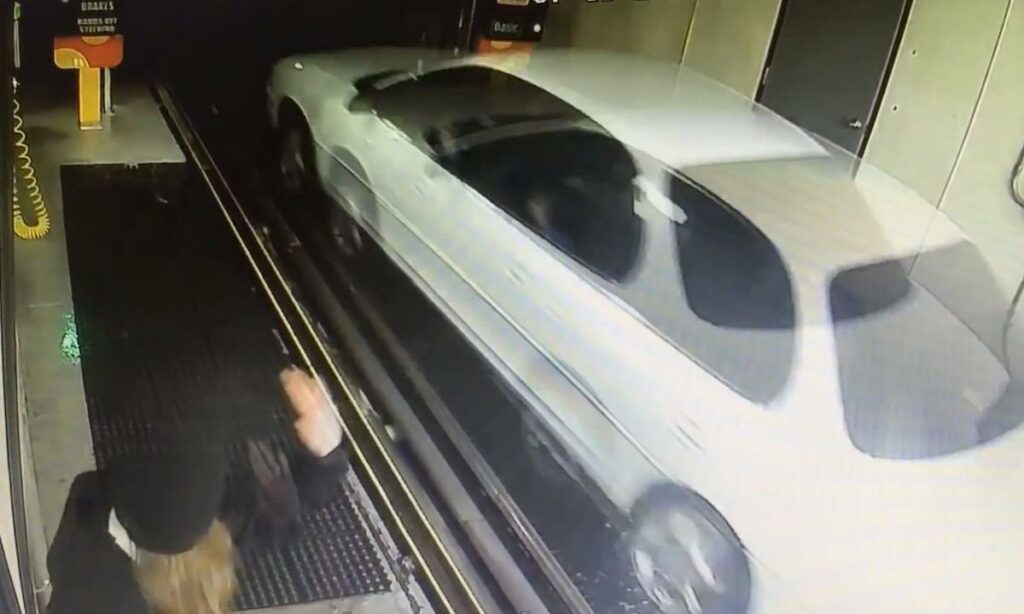 En vit bil körs ut ur ett garage. (AI text)