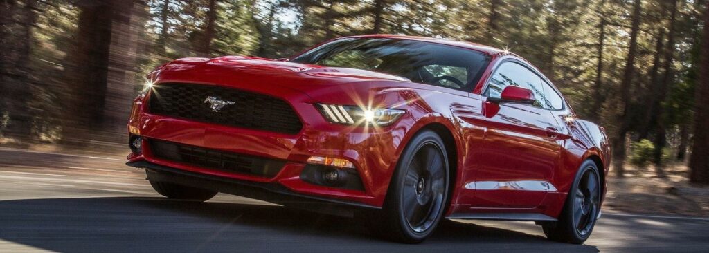En röd Ford Mustang kör nedför en skogsväg. (AI text)