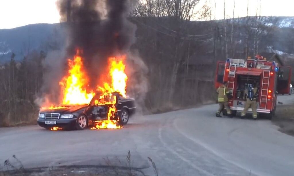En bil brinner på en väg. (AI text)