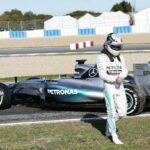 En racerförare promenerar förbi en Mercedes F1-bil. (AI text)