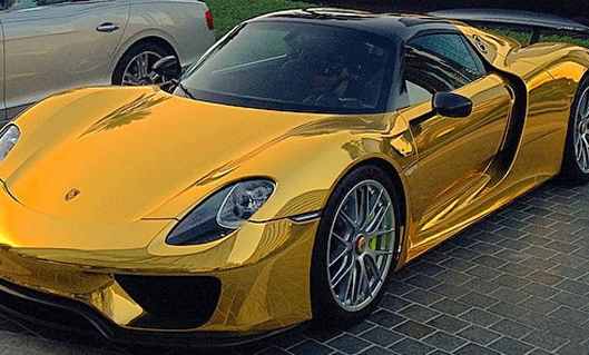 En guld Porsche 918 GTS parkerad framför en villa. (AI text)