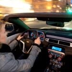 En kvinna kör en cabrioletbil på natten. (AI text)