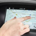 En person pekar på en GPS-skärm i en bil. (AI text)