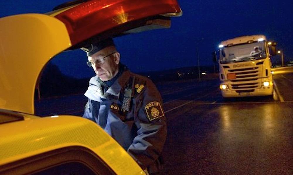 En polisstående står bredvid en gul bil på natten. (AI text)