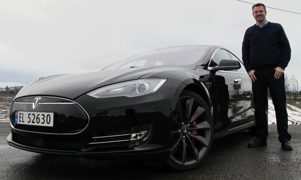 En man står bredvid en Tesla Model S. (AI text)