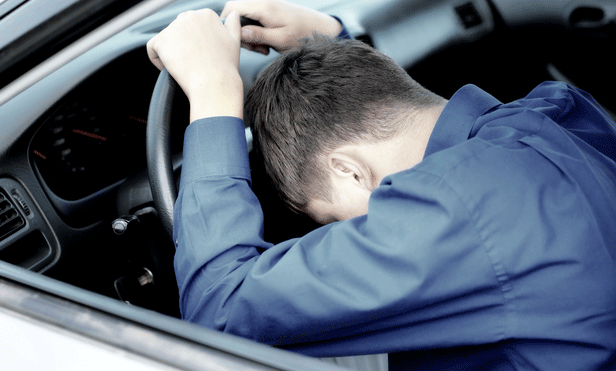 En man sitter i sin bil. (AI text)