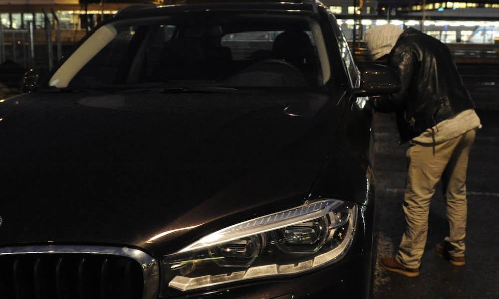 En man står bredvid en BMW X5 på natten. (AI text)