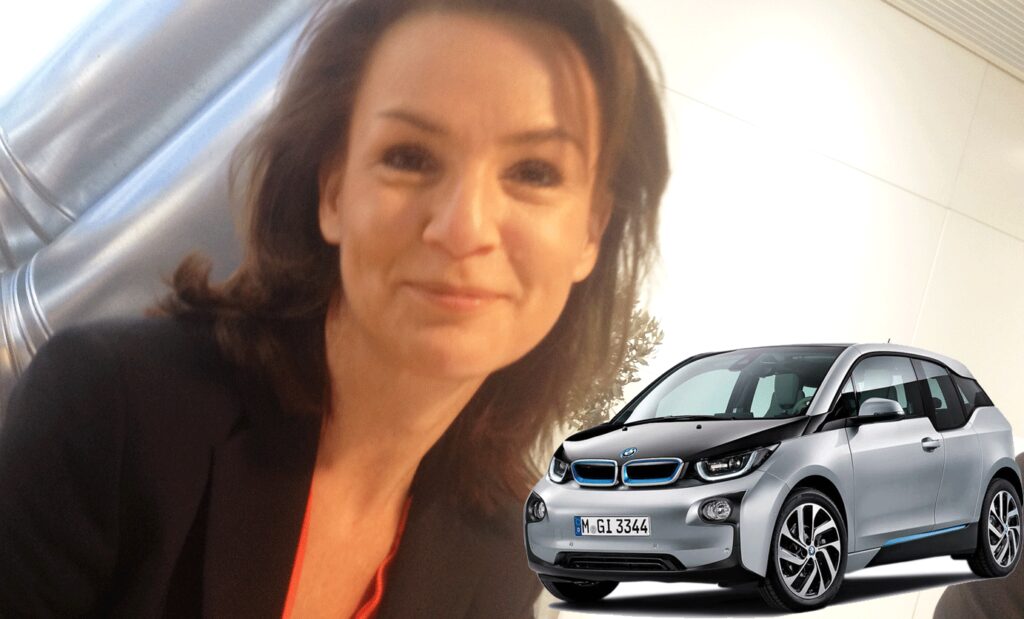 BMW i3 E-drive: En kvinna i kostym tillsammans med en bil. (AI text)