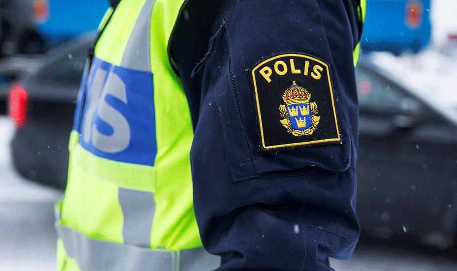 En polis i ett gult västar står framför en bil. (AI text)