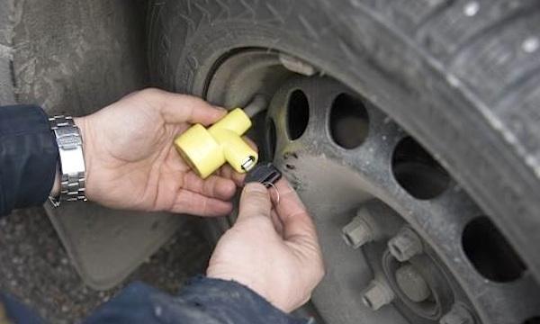 En man monterar en däck på en bil. (AI text)