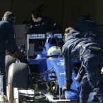 En grupp personer arbetar på en blå formelbil. (AI text)