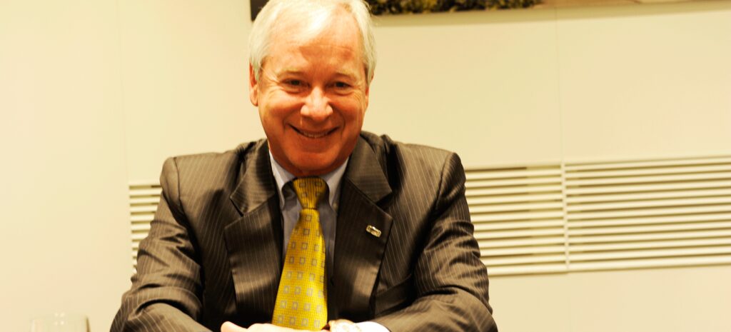 En man i kostym och slips sitter vid en bordet. (AI text)