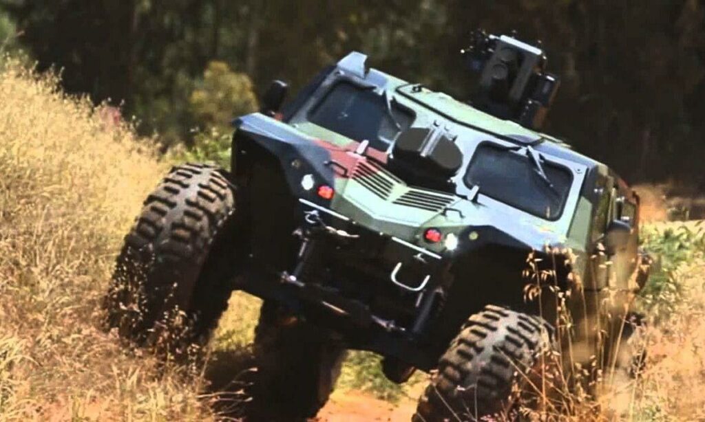 En militärvägfordon kör längs en grusväg. (AI text)