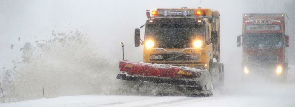en snöröjare som kör längs en snöig väg (AI text)