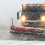 en snöröjare som kör längs en snöig väg (AI text)