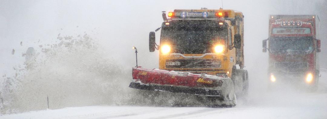 en snöröjare som kör längs en snöig väg (AI text)