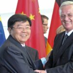 Två män skakar hand framför en flagga. (AI text)