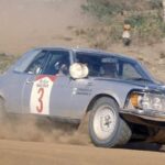 En Mercedes-Benz SL 230-rallybil kör nerför en grusväg. (AI text)