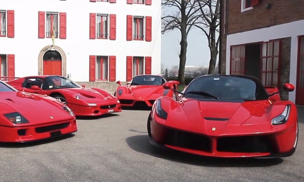 En grupp röda sportbilar står parkerade framför ett byggnad. (AI text)