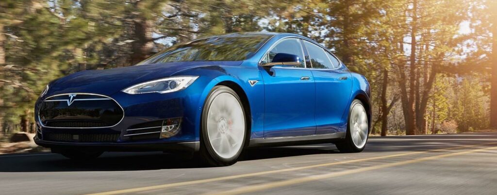 En Tesla Model S kör nedför en väg i skogen. (AI text)