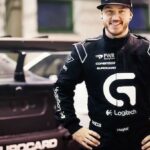 En man står bredvid en racebil. (AI text)