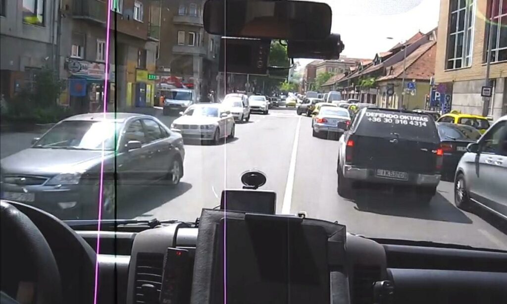 En bil kör nedför en stadsgata. (AI text)