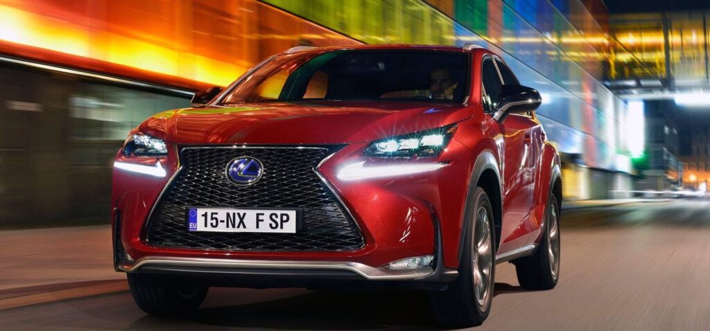 En röd Lexus SUV kör nedför en stadsgata på natten. (AI text)