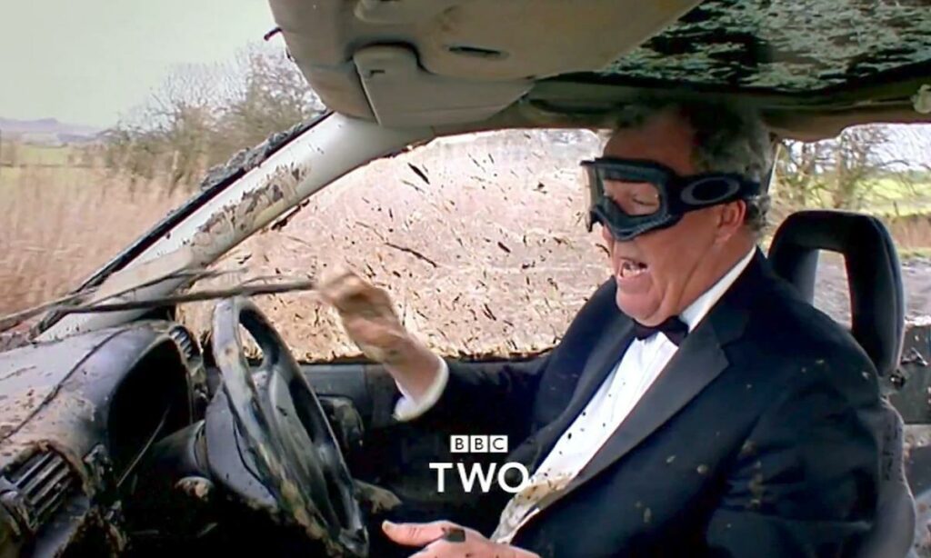 En man i kostym kör en bil. (AI text)