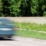 En bil kör genom en väg med en skylt. (AI text)