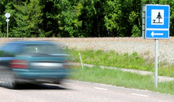 En bil kör genom en väg med en skylt. (AI text)