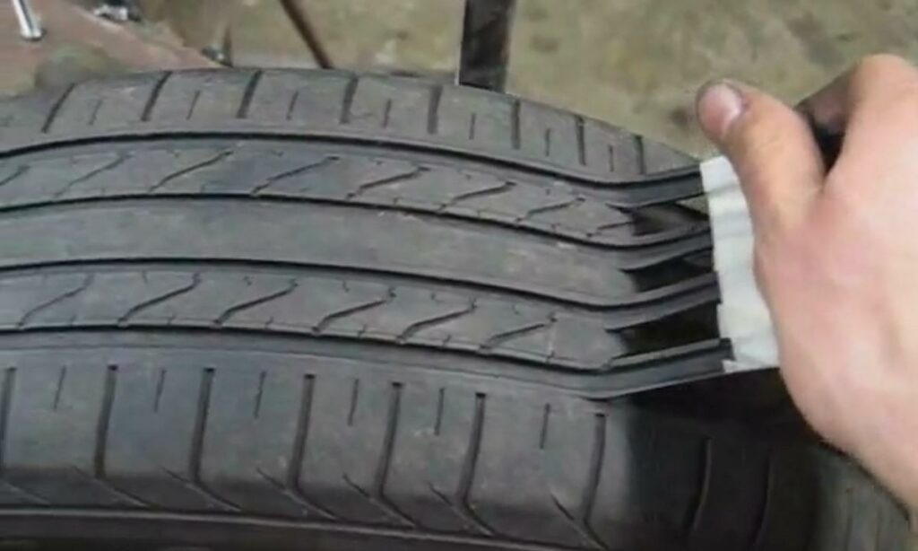 En person tar bort en däck från en bil. (AI text)