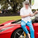 En man sitter på en röd sportbil. (AI text)