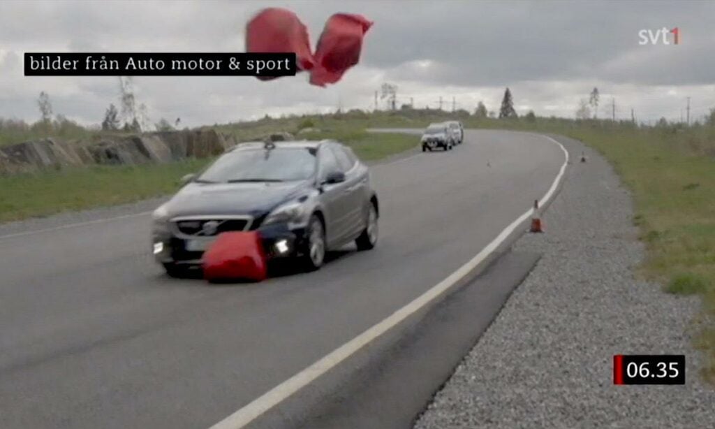 En bil kör nedför en väg med en röd ballong. (AI text)