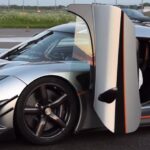 En Koenigsegg K1 supersportbil med öppna dörrar. (AI text)