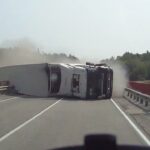 En lastbil ligger uppåt på en motorväg. (AI text)