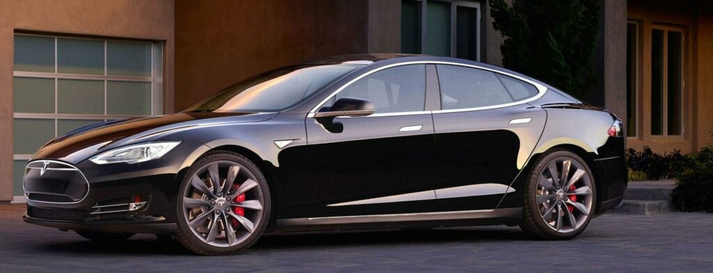 En Tesla Model S parkerad framför en husfasad. (AI text)