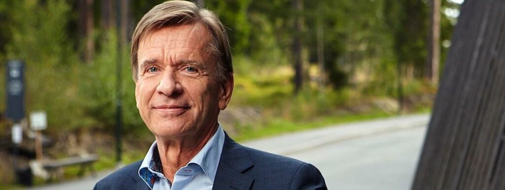 En man i kostym står bredvid en bil. (AI text)