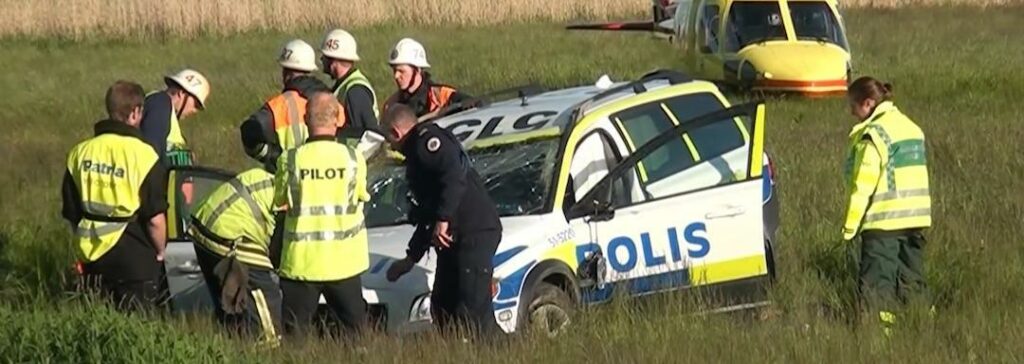 En polishelikopter cirkulerar över en bil som kraschat i en åker. (AI text)