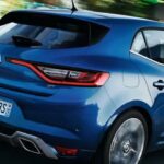 En blå Renault Clio kör nedför en stadsgata. (AI text)