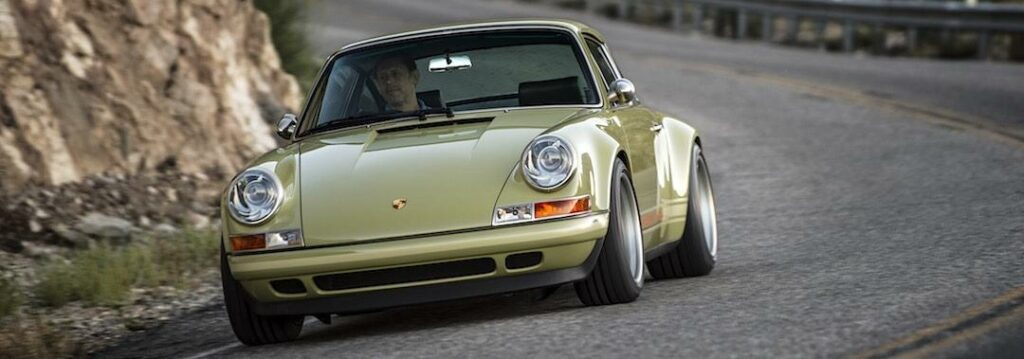 En gröngul Porsche 911 kör nerför en bergsväg. (AI text)