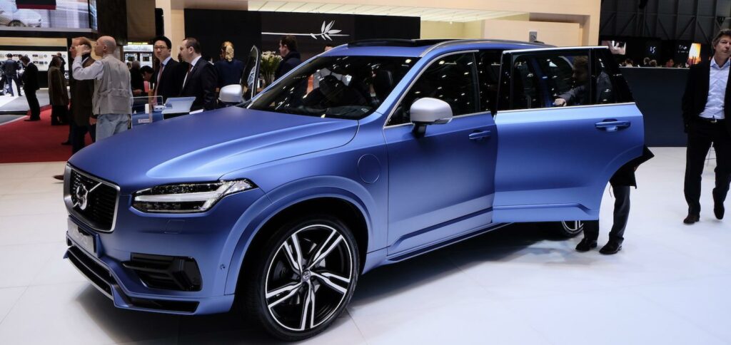 En person står framför en bil på bilsalongen. (AI text)