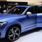 En person står framför en bil på bilsalongen. (AI text)